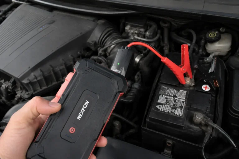 Checking a portable jump starter beside a car battery